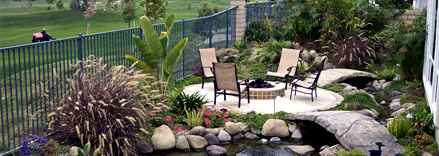 Garden patio with chairs and pond bridge.
